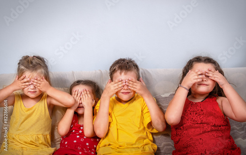 Children sitting on the sofa cover their eyes