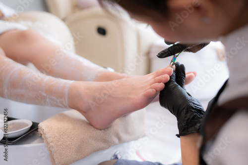 A nail technician is using tools to cut and polish foot of a customer.