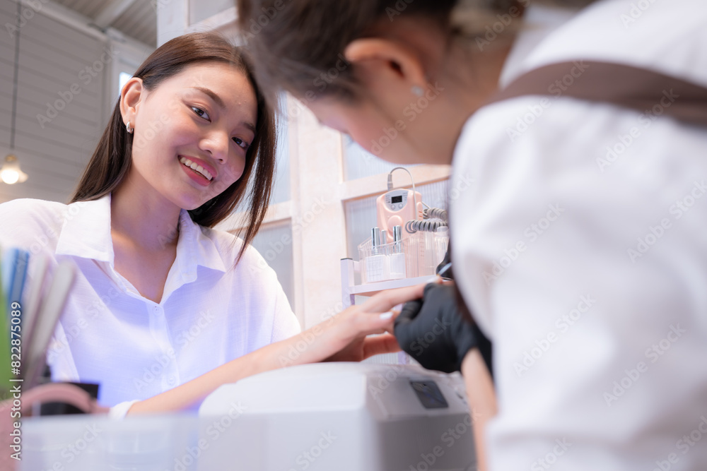 Fototapeta premium A nail technician is painting the nails of a customer.