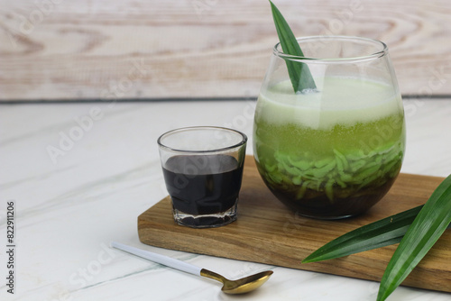 Cendol Pandan, one of popular Indonesian traditional drink, made from rice flour, pandan leaves extract, coconut milk and liquid of palm sugar. White marble background with copy space.