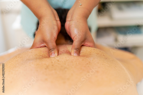 Masseur pressuring trigger points of the back of a woman photo