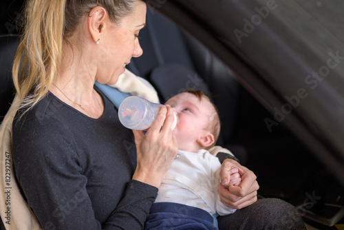 Middle aged blonde woman giving her little baby a bottle