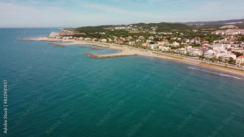 Sitges' coastline with sandy beaches and vibrant town during a sunny day, aerial view Sitges' coastline with sandy beaches and vibrant town during a sunny day, aerial view