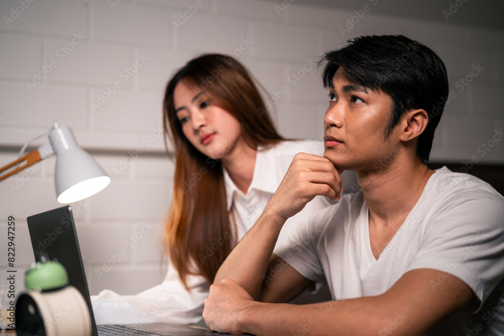 Asian young woman overworking at home at night in bedroom with husband. Asian young woman overworking at home at night in bedroom with husband.