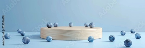 Minimal wooden pedestal for product presentation in pastel blue background, fruit blueberries around photo