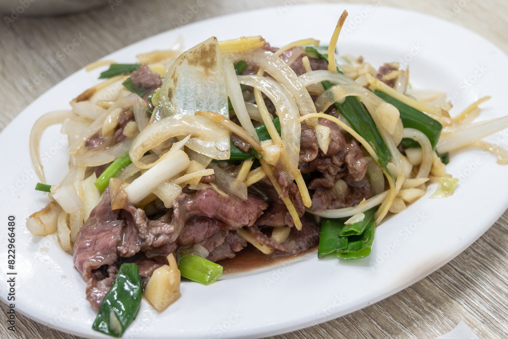 A delicious dish of beef and onions served on a white plate on the table in Tainan, Taiwan A delicious dish of beef and onions served on a white plate on the table in Tainan, Taiwan