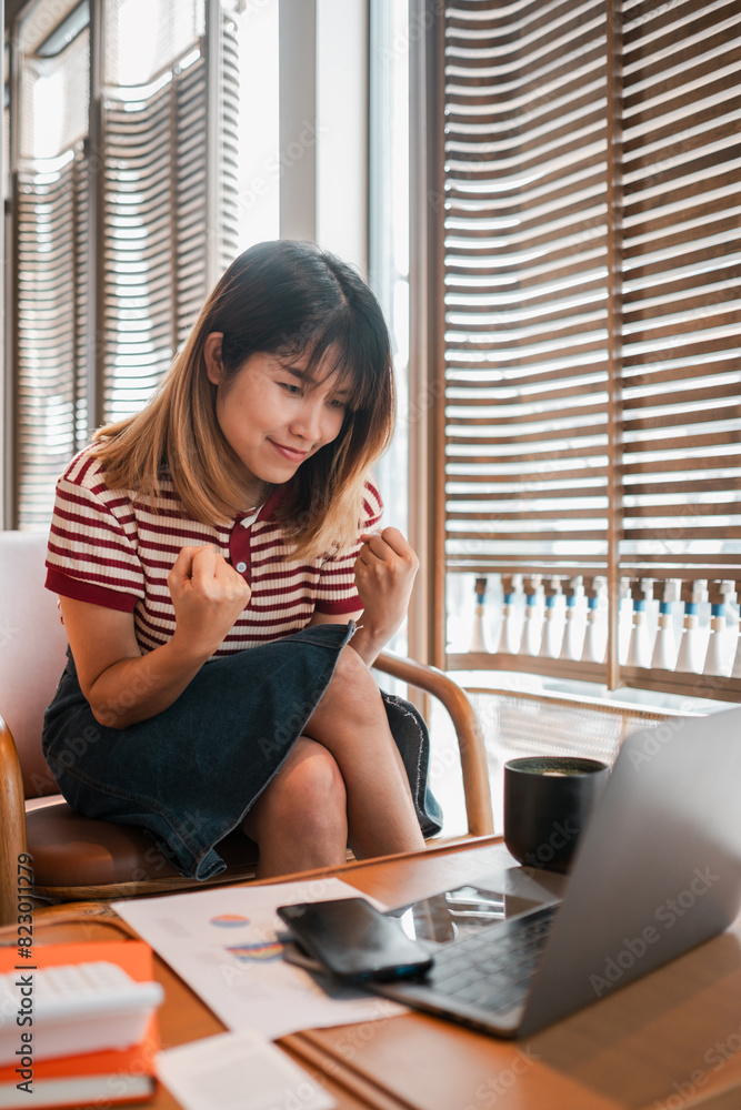 A woman is sitting in a chair with a laptop open in front of her. She is smiling and she is happy A woman is sitting in a chair with a laptop open in front of her. She is smiling and she is happy