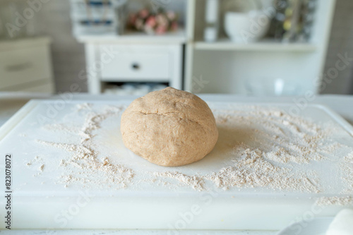 Ball of fresh whole wheat pizza dough on floured surface in the kitchen