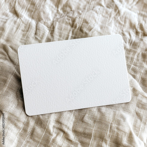 Rectangular white business card mockup with rounded corners on a textured linen surface. photo