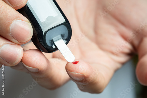 Woman's hands checking diabetes and hyperglycemia with digital blood sugar meter. Healthcare and medical concept