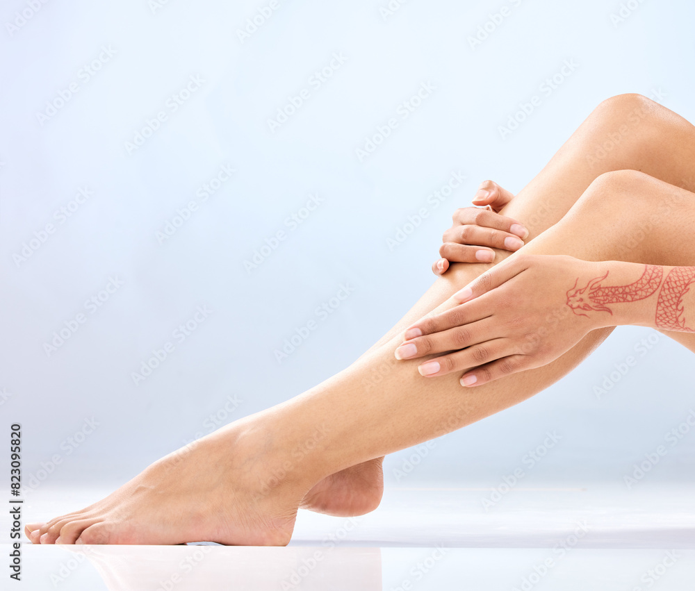 Fototapeta premium Woman, legs and hands with hair removal in skincare for epilation, waxing or grooming on a blue studio background. Closeup of female person or feet with laser treatment for hygiene and dermatology