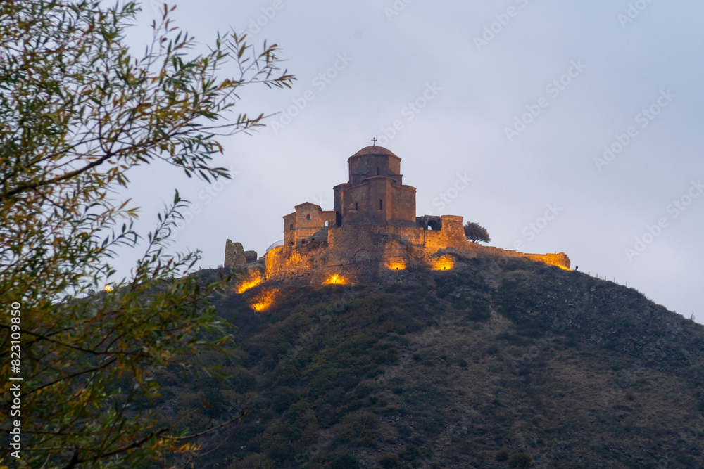 Fototapeta premium Jvari Monastery on the hill illuminated with warm lighting in the early morning