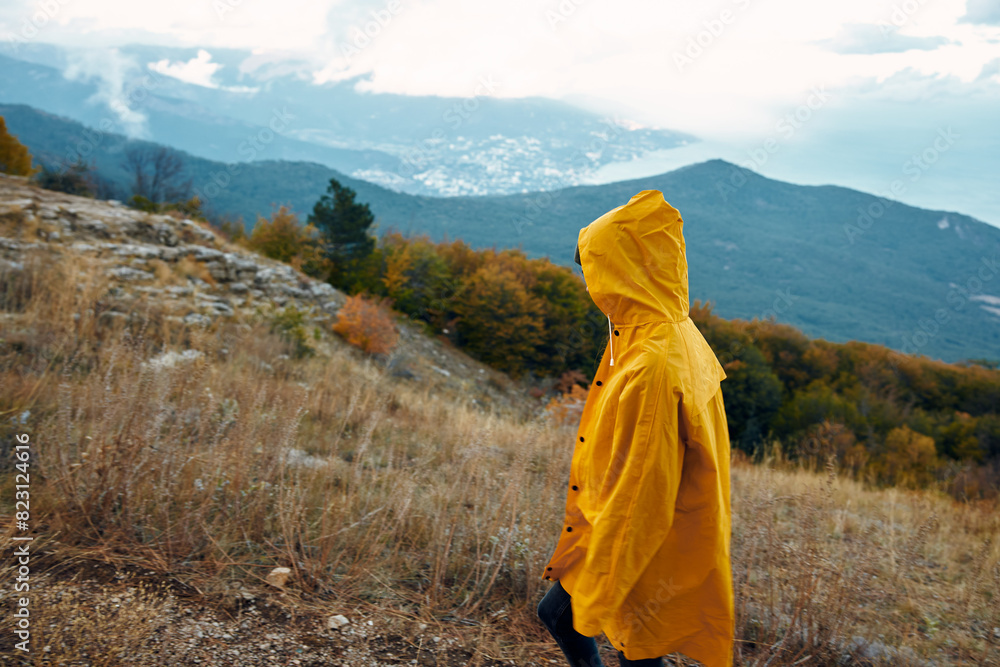 A person in a yellow raincoat admiring the majestic mountain views on a rainy day during a peaceful outdoor adventure
