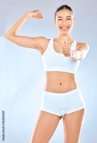 Fitness, portrait and thumbs up with woman in underwear on studio gray background for health or success. Arm, bicep and exercise with hand gesture of athlete for motivation, support or thank you