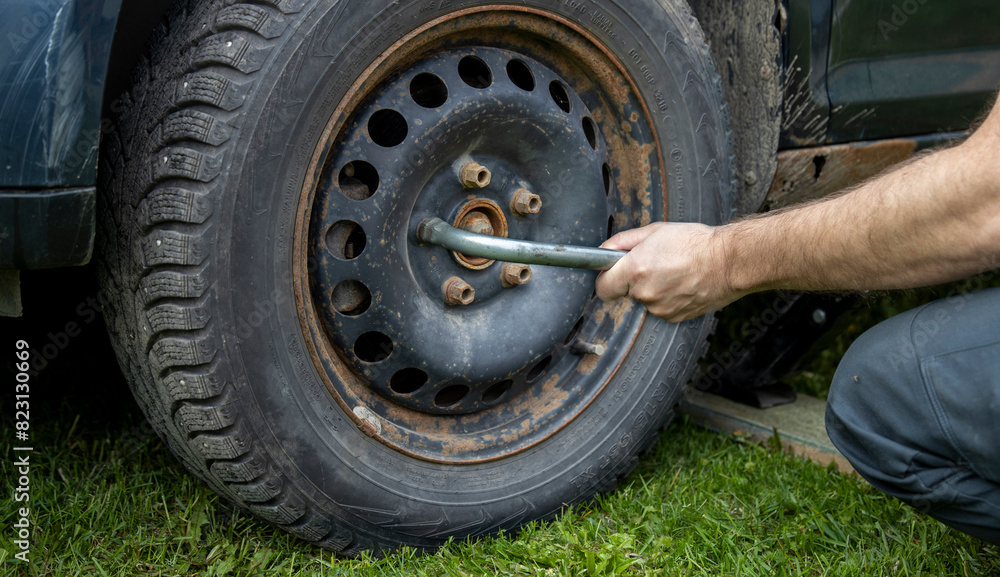 A man meticulously works on the tire of a car, focused on fixing any issues and ensuring it is in perfect condition. A man meticulously works on the tire of a car, focused on fixing any issues and ensuring it is in perfect condition.