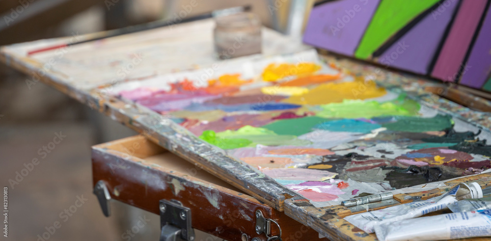 A vibrant artist's palette with an array of oil and acrylic paints, showcasing the creative process of mixing colors, set up on an easel, ready for outdoor painting A vibrant artist's palette with an array of oil and acrylic paints, showcasing the creative process of mixing colors, set up on an easel, ready for outdoor painting