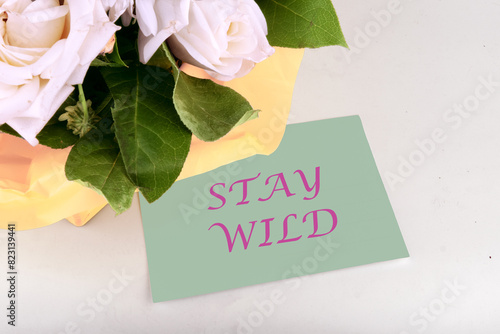 Financial concept meaning STAY WILD words written on a piece of paper near a bouquet of flowers