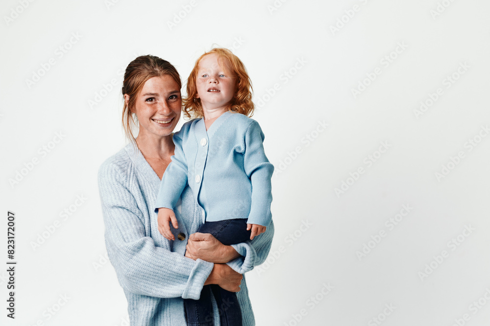 Mother and daughter in matching blue outfits posing together against a white background for family photoshoot Mother and daughter in matching blue outfits posing together against a white background for family photoshoot