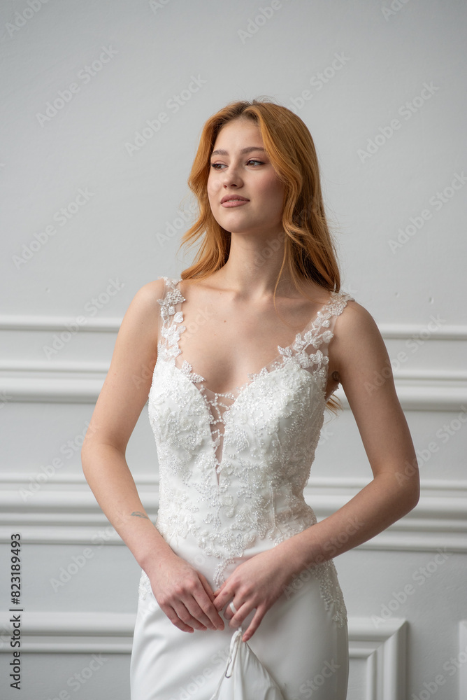 Fototapeta premium Beautiful young woman bride in fashion wedding dress in white interior