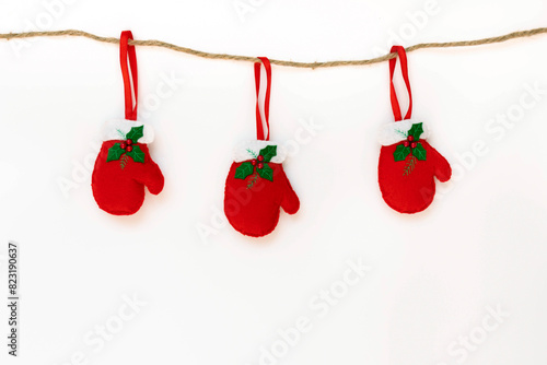 Red gloves hanging on a rope isolated on the white background with copy space. The atmosphere of Christmas and New Year. Christmas banner, mock up