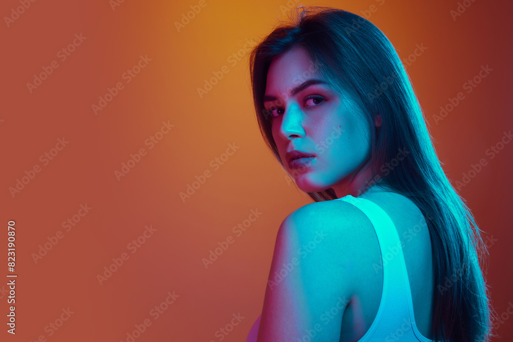 Portrait of young beautiful woman with long, dark hair, looking over her shoulder in neon light against gradient background. Concept of beauty and care, cosmetology, wellness, spa treatments. Ad Portrait of young beautiful woman with long, dark hair, looking over her shoulder in neon light against gradient background. Concept of beauty and care, cosmetology, wellness, spa treatments. Ad