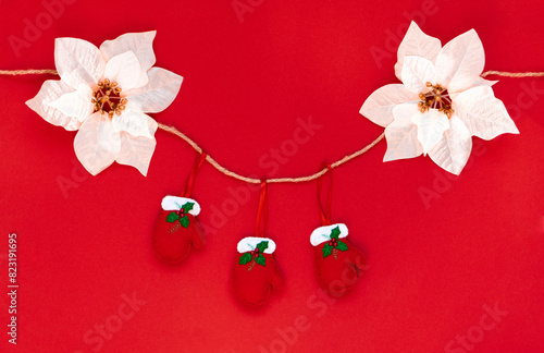 Red gloves hanging on a rope isolated on the red background with copy space. The atmosphere of Christmas and New Year. Christmas banner, mock up