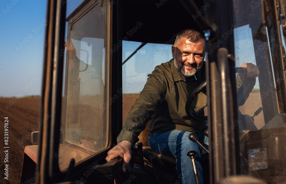 Portrait of satisfied farmer sitting in a tractor preparing to cultivate the land with a tractor. Portrait of satisfied farmer sitting in a tractor preparing to cultivate the land with a tractor.