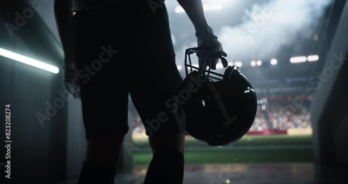 Cinematic Football Walkout: Successful Player Entering a Massive American Football Stadium to the Noise and Cheering of the Anticipating Fans. Epic Close Up Back View of an Anonymous Athlete photo