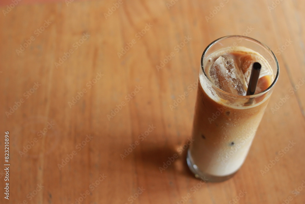 Iced milk coffee with palm sugar and straw on wooden table. Iced milk coffee with palm sugar and straw on wooden table.