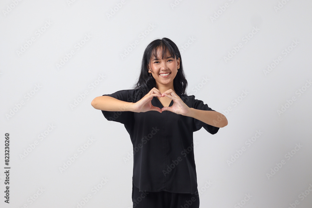 Portrait of attractive Asian woman in casual shirt speaks about own feelings, makes heart gesture over chest, expresses sympathy and love, smiles positively. Isolated image on white background Portrait of attractive Asian woman in casual shirt speaks about own feelings, makes heart gesture over chest, expresses sympathy and love, smiles positively. Isolated image on white background