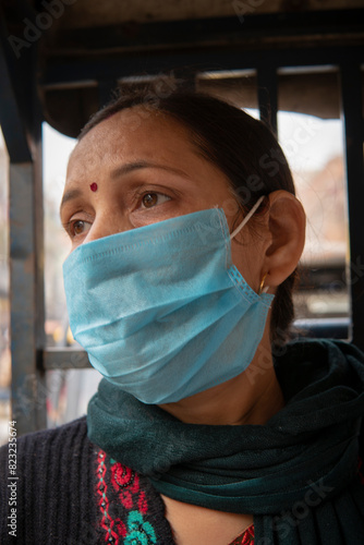 Close up portrait of Indian mature woman sitting in public transport electric auto rickshaw with protective face mask.