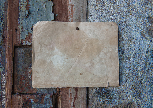 Old paper advertisement hanging on aged wall nailed by rusty doornail photo