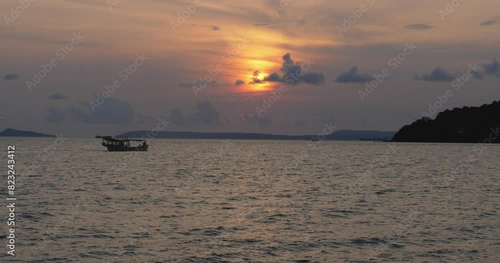 Small, wooden fishing boat floating on a calm ocean at cloudy sunset. The boat is silhouetted against the vibrant colors of the sunset. Small, wooden fishing boat floating on a calm ocean at cloudy sunset. The boat is silhouetted against the vibrant colors of the sunset.