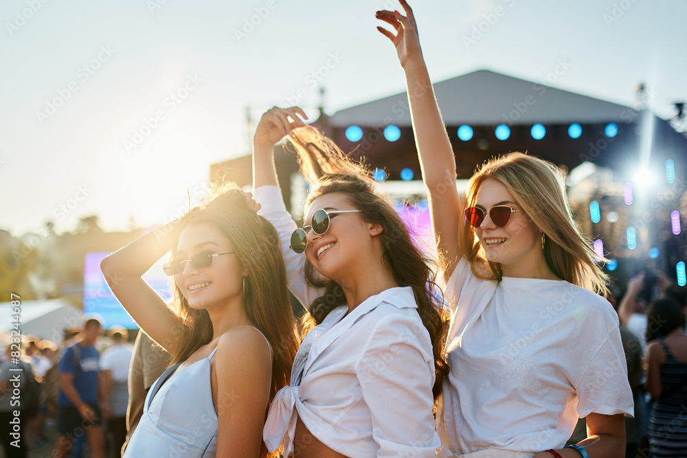 custom made wallpaper toronto digitalGirls in white tops enjoy summer music festival on sandy beach at sunset. Arms raised, they dance, laugh, celebrate friendship in bright sunlight, crowd, stage in background. Holiday, youth culture.