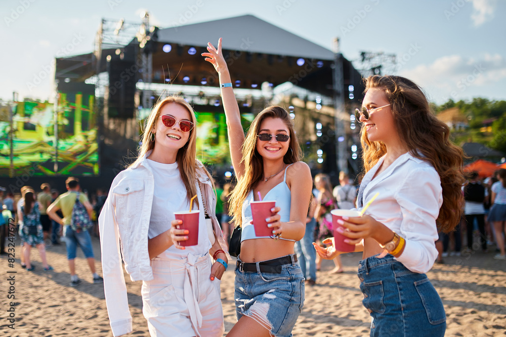 custom made wallpaper toronto digitalGirls toast with cold drinks at beach music fest in summer, smiling, wearing sunglasses, with stage, people in background. Celebration, fun, youth lifestyle. Females enjoying party, ocean nearby.