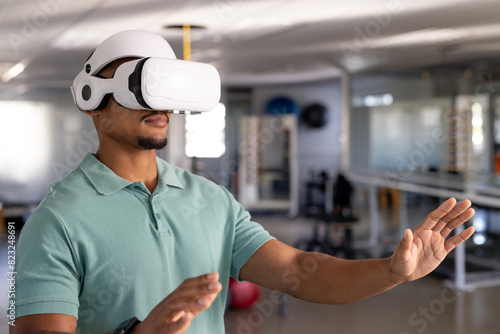Biracial male physical therapist in VR headset reaches out at gym rehabilitation center photo