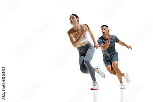 Man and woman wearing sports clothes mid-stride during sprinting exercise against white studio background. Concept of people in sport, healthy lifestyle, teamwork, motivation. Ad