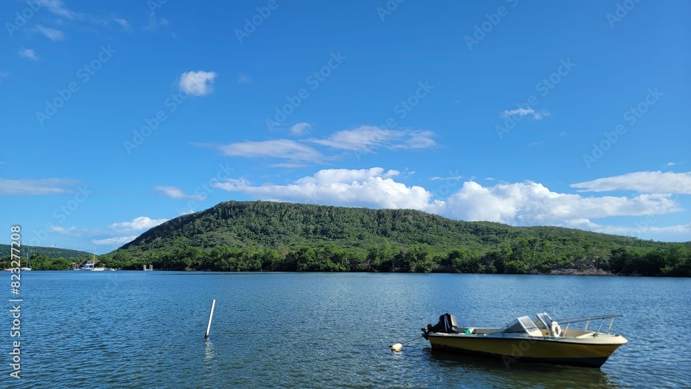 Small boat on a picturesque shoreline, with a backdrop of green mountains Small boat on a picturesque shoreline, with a backdrop of green mountains