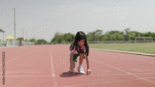 Portrait Thai Asian kid girls aged 8 to 10 years, looking cute in exercise clothes. Being at the starting point To start jogging in the red treadmill stadium Running gives her a healthy body.