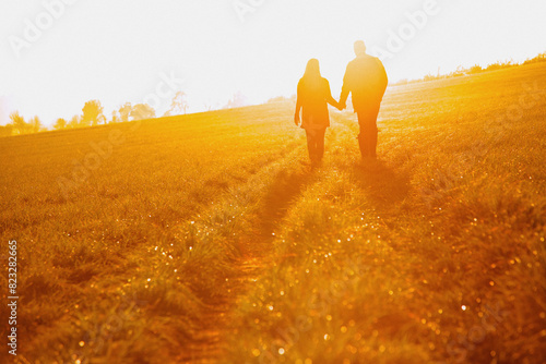 Couple Walking in a Field Holding Hands
 photo