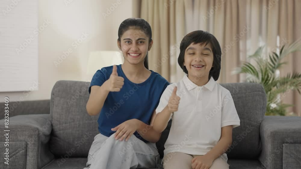 Cheerful Indian siblings showing thumbs up to the camera