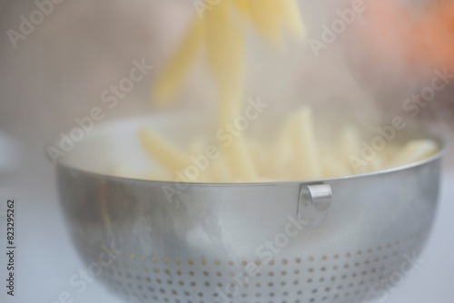 Draining penne pasta into a colander
 photo