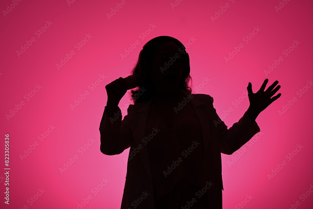 Silhouettes of mature woman singing with microphone against pink background