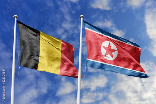 3d illustration. Belgium and North Korea Flag waving in sky. High detailed waving flag. 3D render. Waving in sky. Flags fluttered in the cloudy sky. photo