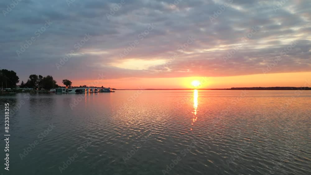 Tranquil lake at sunrise, boats floating on water, red sky, and morning breath. Tranquil lake at sunrise, boats floating on water, red sky, and morning breath.