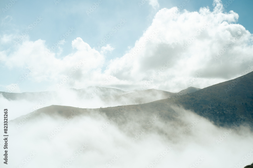 Mountain peaks emerging from a sea of clouds under a blue sky Mountain peaks emerging from a sea of clouds under a blue sky