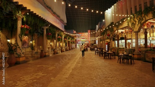Back shot of an adult man walking in an Italian-style street with urban buildings in Yas Island, UAE photo