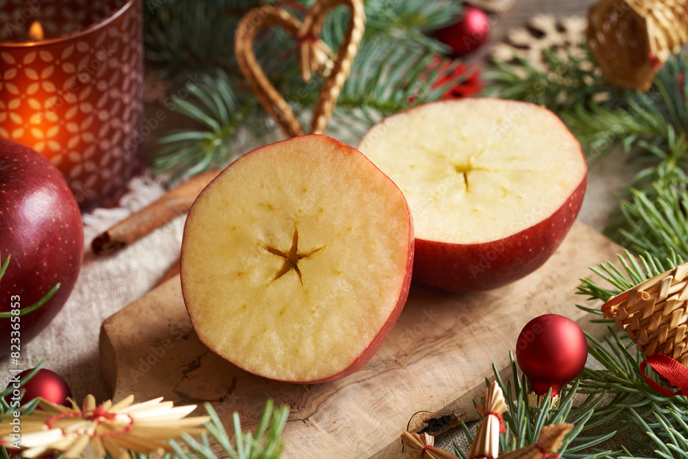 Halved red apple with a star in the middle with Christmas straw ornaments and  baubles