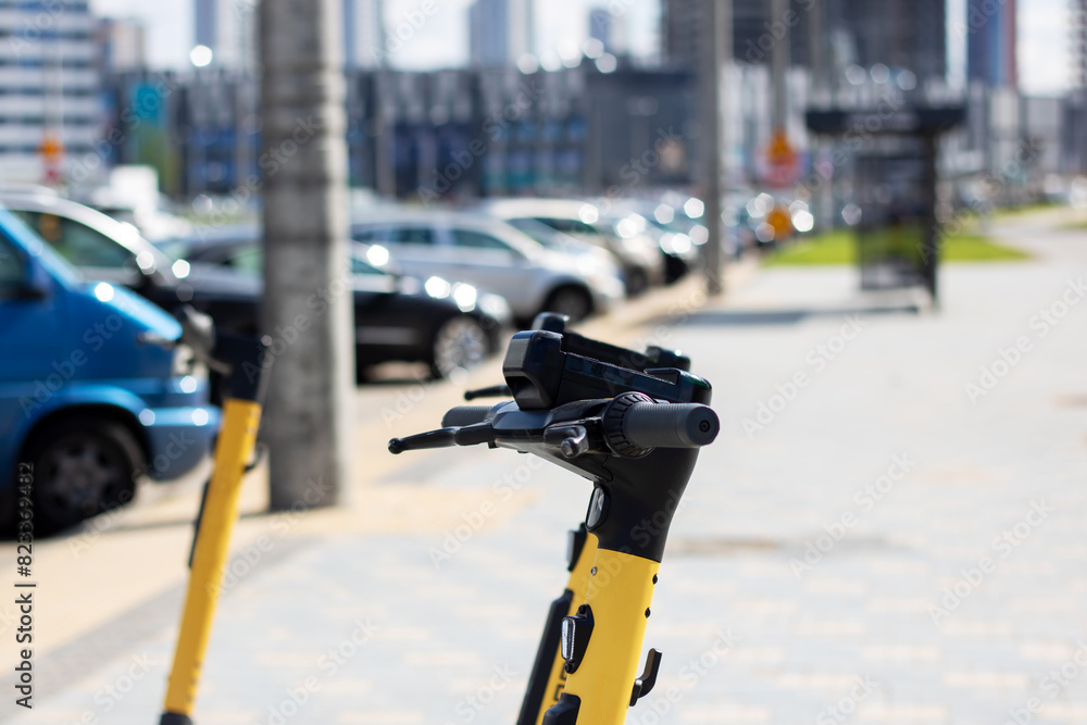 A yellow and black scooter with bicycle handlebar parked on the city road A yellow and black scooter with bicycle handlebar parked on the city road