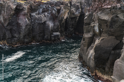 A beautiful coastal area in eastern part of Japan. A clear blue sky and an orange sunrise reflects on the sea water. A big rock formation in the coast line. Island from the distance.